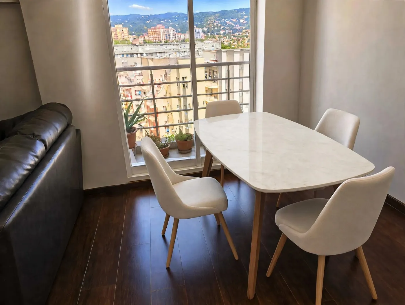 Comedor con mesa de cubierta blanca tipo mármol y sillas tapizadas, instalado frente a una ventana con vista a Bogotá