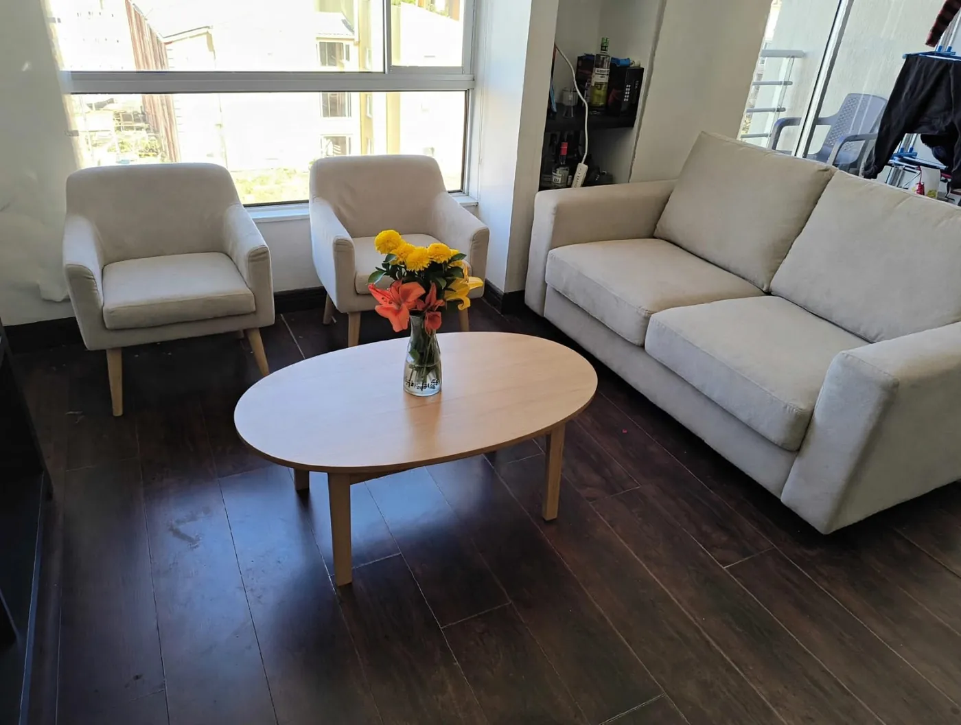 Sala con sofá, dos poltronas y mesa de centro ovalada en madera