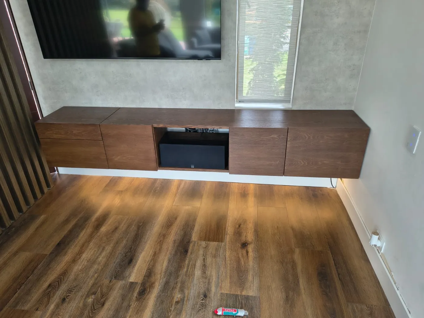 El mismo mueble de TV terminado en nogal e instalado en una sala